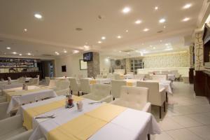 un restaurante con mesas blancas y sillas blancas en Hotel Talija, en Banja Luka