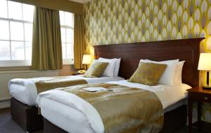 a hotel room with two beds and two windows at King's Head Hotel By Greene King Inns in Wimborne Minster