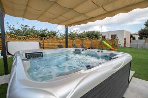 a hot tub under an umbrella in a yard at Le Villette di Villa Aurora in Lampedusa