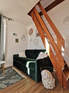 sala de estar con sofá verde y escaleras de madera en Au Coeur des Rousses, en Les Rousses