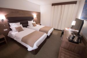 a hotel room with two beds and a television at Hôtel Bastide in Onet le Château