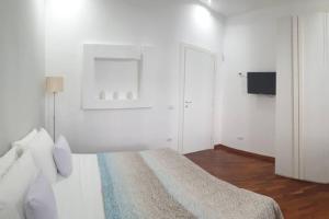 a white bedroom with a bed and a tv at Casual Life Suite in Reggio di Calabria