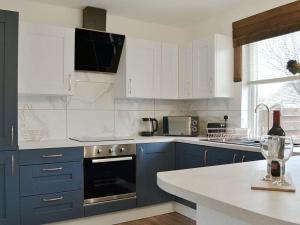 a kitchen with blue cabinets and a bottle of wine at The Dookit - Aviemore Town House in Aviemore