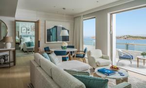 a living room with a couch and a table and chairs at Four Seasons Astir Palace Hotel Athens in Athens
