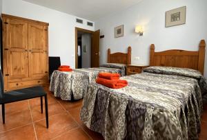 three beds in a room with orange towels on them at Apartamentos de turismo rural Las Eras in Castelserás +51 photos