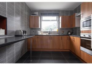 eine Küche mit Holzschränken, einem Waschbecken und einem Fenster in der Unterkunft Spacious Bungalow in Romford with parking in Romford