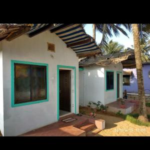 a white house with a palm tree in front of it at Prafulla Homestay in Kārwār