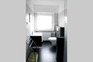 baño con aseo y ventana en Traumhafte Kurstadt Apartment Moderne 2ZKB Balkon PKW Stlp Self-Check-in, en Bad Nauheim