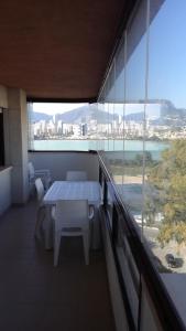 カルプにあるAPTO Acceso Directo Playa La Fossa Calpeの大きな窓のある客室で、テーブルと椅子が備わります。