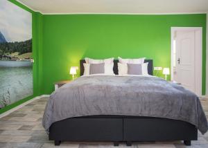 a bedroom with a large bed with a green wall at Haus Jungmann in Hallenberg