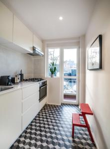 a kitchen with white cabinets and a red bench in front of a window at Mini loft 1 bedroom 2 steps from Av Louise in Brussels