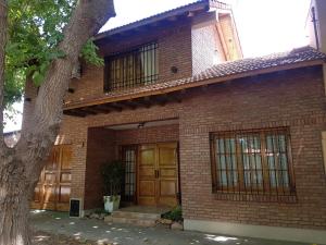 una casa de ladrillo con puertas de madera y un árbol en Casa Luminosa en San Rafael