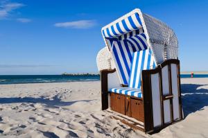 - une chaise bleue et blanche assise sur la plage dans l'établissement DER SÜDSCHWEDE ... Dein Gästehaus mitten in Zingst und nah zum Strand, à Zingst