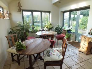 una sala da pranzo con due tavoli, sedie e finestre di Herb Cottage a Bradford on Avon