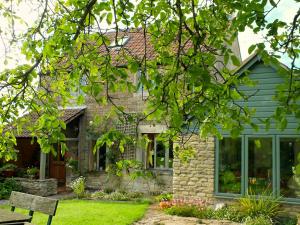 una casa de piedra con un banco en el patio en Herb Cottage en Bradford on Avon