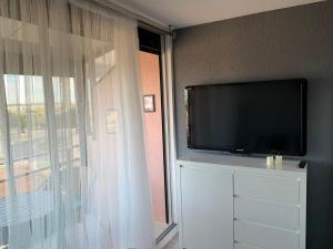 TV de pantalla plana en un tocador con ventana en Studio climatisé à 5 minutes de la plage en Le Grau-du-Roi