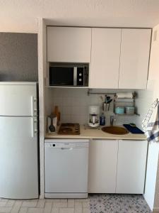 uma cozinha com armários brancos e um frigorífico branco em Studio climatisé à 5 minutes de la plage em Le Grau-du-Roi