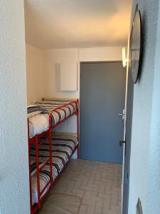 ル・グロー・デュ・ロワにあるStudio climatisé à 5 minutes de la plageの二段ベッドとドアが備わる小さな客室です。