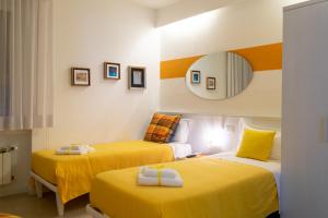 two beds in a room with yellow sheets and a mirror at Marconi Rooms 1, 2, 3 Casa Stella in Verona