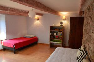 a bedroom with a red bed and a book shelf at gîte de la cheneau in Rochesson