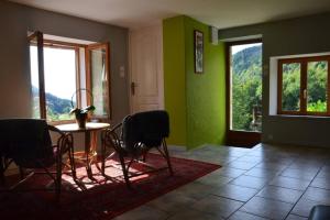 Rochesson的住宿－gîte de la cheneau，一间拥有绿色墙壁和桌椅的用餐室