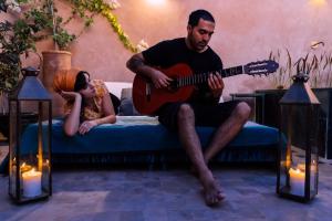 facet grający na gitarze obok małej dziewczynki w obiekcie Riad Albatoul w Marakeszu