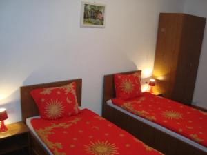 two beds in a small room with red sheets at Apartament Miruna Sibiu Filarmonicii in Sibiu