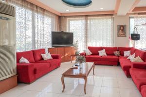 a living room with red couches and a tv at Faliraki Dream Studios & Apartments in Faliraki