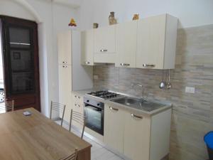 a kitchen with white cabinets and a sink and a table at casa francesca in Castellammare del Golfo