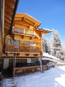 a log cabin with a balcony in the snow at Ferienhaus Schöneggerhof in Innervillgraten