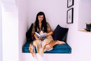 a woman sitting on a bed reading a book at Riad Albatoul in Marrakesh