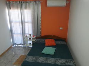 um pequeno quarto com uma cama com uma parede laranja em Alojamiento 1 Lili y Víctor em Puerto Iguazú