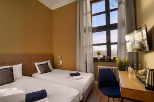 a bedroom with two beds and a desk and a window at Apartamenty Oliwka in Elblag