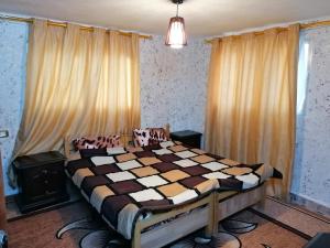 a bedroom with a bed with a checkered blanket at Mhna guest house in Ajloun