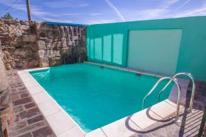 a large swimming pool with a green wall and a building at Casa Rural El Cartero in Carpio de Azaba