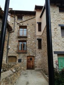 Casa de piedra antigua con puerta y ventanas de madera en Apartamento Rafa en Valdelinares