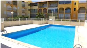 a large blue swimming pool in front of a building at Appartement T2 avec son rez de jardin de 40 m2 5 couchages 250m de la plage et 15km de l'Arena in Narbonne-Plage