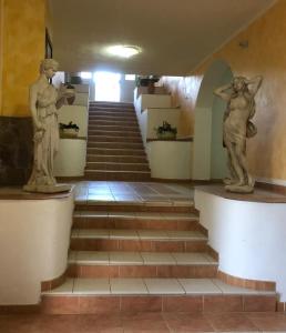 twee standbeelden van mensen op een trap in een gebouw bij HOTEL FUNTANA E DONNE in Ottana