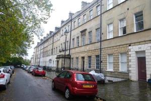 un coche rojo estacionado frente a un edificio en Bath Garden Apartment, en Bath