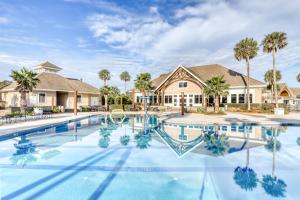 a swimming pool in front of a house with palm trees at Baywood Luxury in Seabrook Island