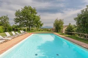 a swimming pool with chaise lounge chairs and a swimming pool at Agriturismo Cerreto in Pienza