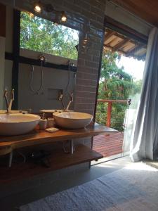 a bathroom with two sinks on a counter with a window at Pousada Santa Vila in Serra do Cipo