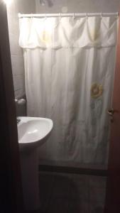 een badkamer met een wit douchegordijn en een wastafel bij Hotel Las 40 in Villa Gesell