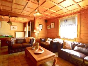 a living room with leather couches and a table at Spacious chalet in Ovifat Waimes with sauna in Ovifat
