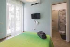 a bedroom with a green bed and a television on the wall at B&B La Tinta in Baronissi