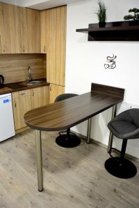 uma mesa de madeira numa cozinha com 2 cadeiras em Dentissimi vendégszobák em Mosonmagyaróvár