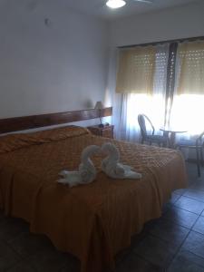 dos cisnes están sentados en la parte superior de una cama en Hotel Las 40 en Villa Gesell
