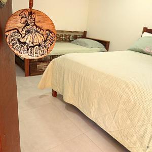 a bedroom with two beds and a wooden sign at Recanto Abayomi in Ilha do Mel