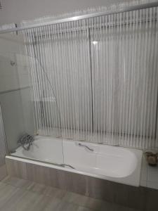 eine weiße Badewanne im Bad mit Glaswand in der Unterkunft Oh So You Guesthouse in Kroonstad