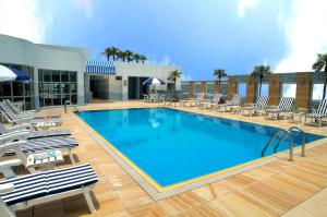 ein großer Pool mit Stühlen und ein Gebäude in der Unterkunft Metropark Hotel Kowloon in Hongkong